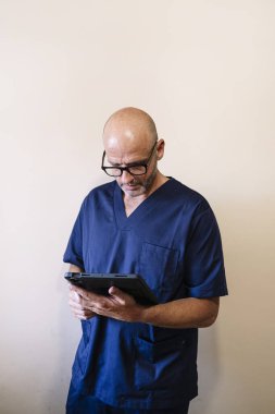 Tablet sağlık görevlisiyle gülümseyen doktorun stüdyo portresi.