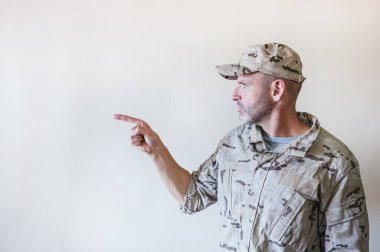 Kamuflajlı üniformalı bir adam eli ve parmağı yana bakıyor..