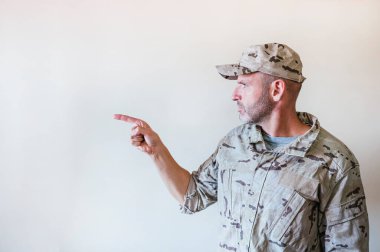 Kamuflajlı üniformalı bir adam eli ve parmağı yana bakıyor..