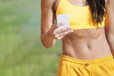 Akıllı telefonunu kullanan tanınmayan bir bayan atlet.