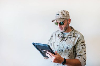 Kamuflaj üniformalı beyaz adam tablet kullanıyor. Teknoloji konsepti..