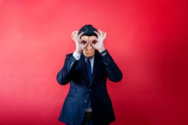 Maymun maskeli bir iş adamı parmaklarından bakıyor..