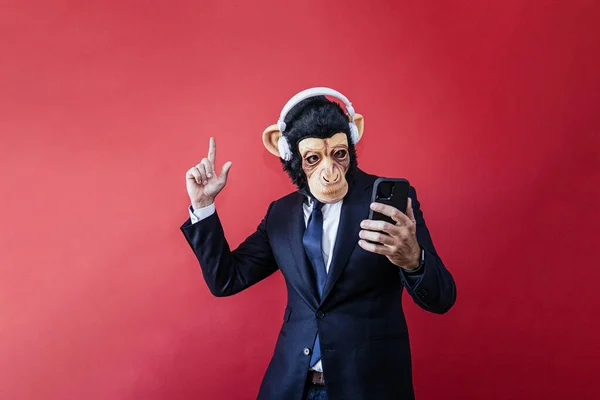 Businessman in monkey mask dancing with headphones and smartphone