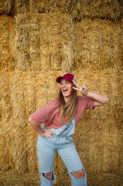 Saman balyalarının önünde gülen bir kadın elleri kalçasında.