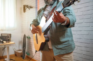 Pencere ve kaykay yanında akustik gitar çalan adam.