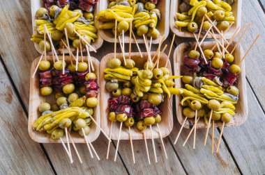 Tabaklar dolusu zeytin ve biber şişleri ahşap masada..