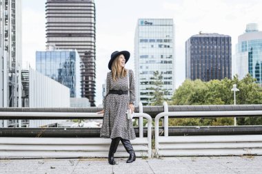 Şehir binalarının poz verdiği uzun desenli elbiseli bir kadın..