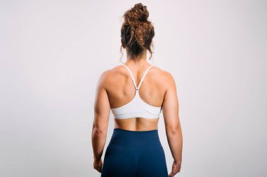 Sırtı kameraya dönük bir kadın sırt ve omuz kaslarının tanımını gösteriyor.