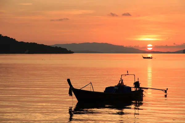 Denizde yüzen tekne ile gökyüzünün portakal gölge ile günbatımı sahne
