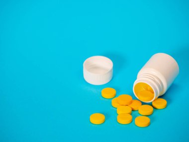 Sarı haplar ve plastik beyaz şişe.