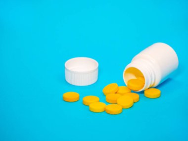 Sarı haplar ve plastik beyaz şişe.