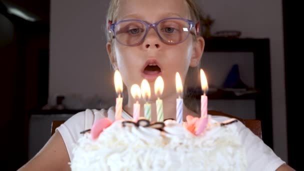 Aranyos kisfiú, aki otthon ünnepli a születésnapját, gyertyákat fúj édes tortán. — Stock videók