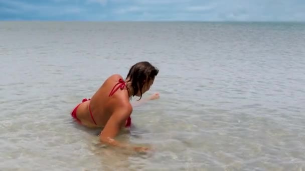 Mujer joven en traje de baño rojo en la playa en la costa del mar — Vídeos de Stock