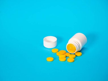 Sarı haplar ve plastik beyaz şişe.