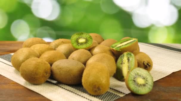Reife ganze und halbe Kiwi-Früchte auf grünem Hintergrund — Stockvideo