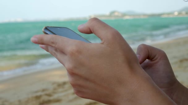 Deniz Suyu Arkaplanı Üzerinde Siyah Akıllı Telefon Kullanan Kadın Elleri — Stok video