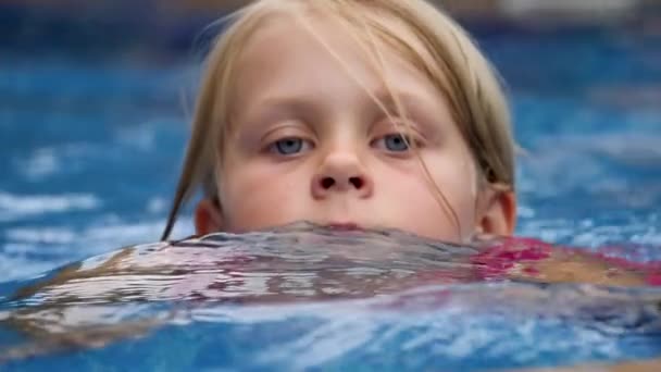 Активная маленькая девочка плавает в бассейне — стоковое видео