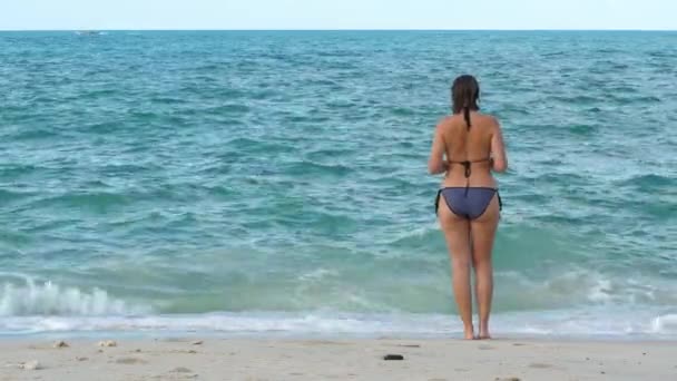 Tan woman stay on sandy beach and looks on water sea background — Stock Video