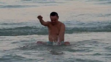 Su sıçratan ve deniz dalgalarında yüzen komik bir adam.