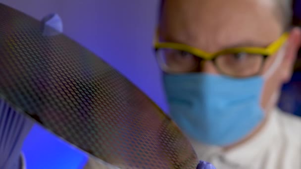 Young engineer in yellow glasses holds in hand wafer crystalline silicon — Stock Video