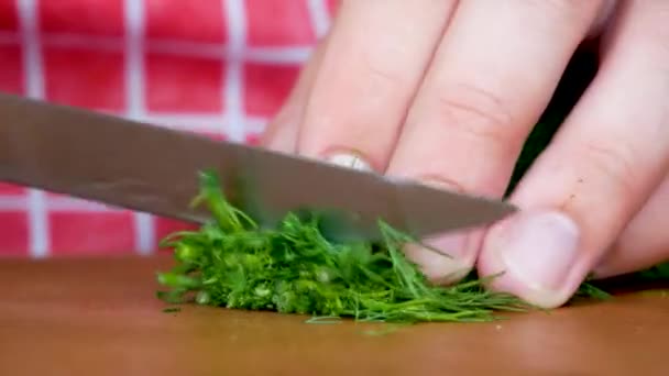 Κομμένη χούφτα άνηθο με μαχαίρι σε ξύλινη σανίδα κουζίνας — Αρχείο Βίντεο