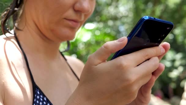 Perempuan menggunakan smartphone biru pada latar belakang pohon palem — Stok Video