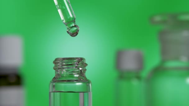 Heldere druppel biologische etherische olie valt uit pipet in glazen fles — Stockvideo