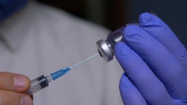 Tanınmayan hemşire şırıngaya çözeltiyi şişeden şırınga ile çekiyor