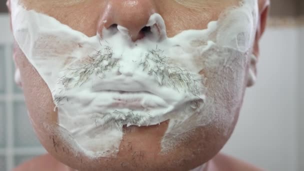 Knappe jongeman met schuim op zijn gezicht scheren met scheermes — Stockvideo