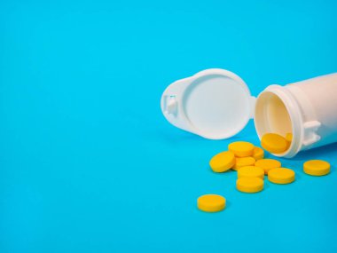 Sarı haplar ve plastik beyaz şişe.