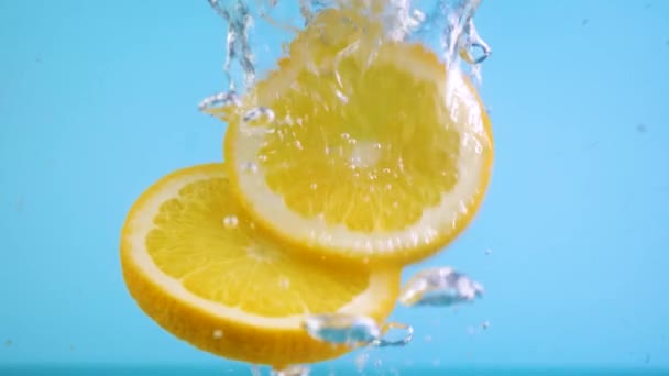 Fruta naranja en rodajas caen bajo el agua — Vídeo de stock