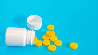 Sarı haplar ve plastik beyaz şişe.