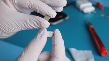 Ekipman mühendisi, beyaz eldivenleri tut ve nano-SIM kartlara bak.
