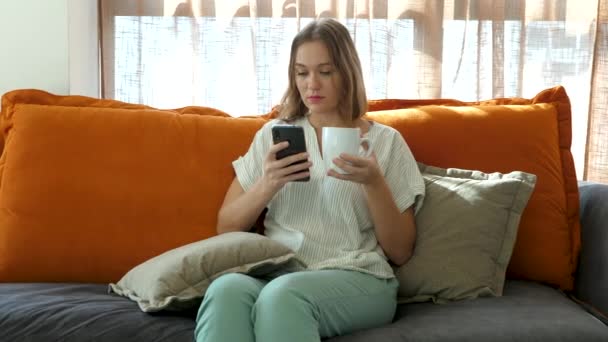 Söt kvinna med smartphone och dricker kaffe på morgonen på solig dag — Stockvideo