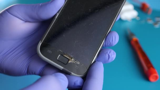 Males hand in blue gloves holds black broken smartphone — Αρχείο Βίντεο