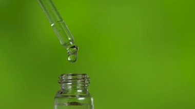 Yeşil arka planda pipetten damlayan tıbbi yağ