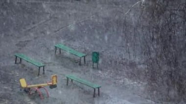 Baharda şehir parkında çocuk parkına kar yağıyor.