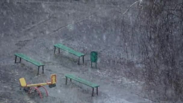 Fallande snö på lekplats i stadsparken på våren — Stockvideo