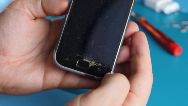 Неузнаваемый техник держит смартфон со сломанным сенсорным дисплеем — стоковое видео