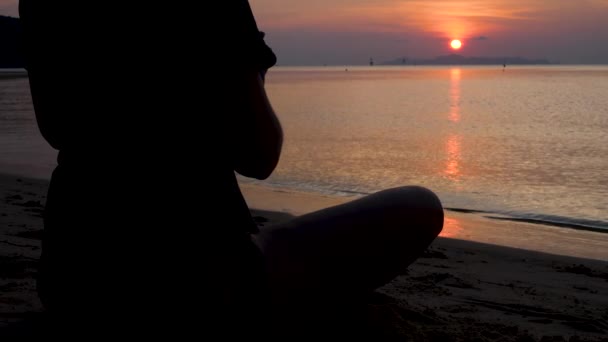 Vrouw zit in lotuspositie en doet asana yoga op zonsondergang — Stockvideo