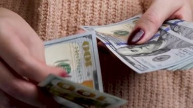 Mağazadaki kadın alıcı 100 Amerikan doları sayıyor.