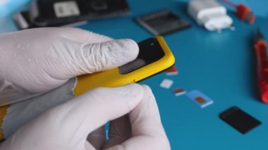 Tamirci, sarı akıllı telefondan nano kartlı SIM tepsiyi çıkardı. 