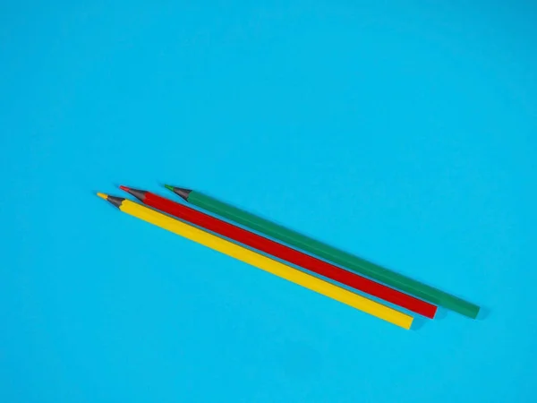 Желтые, зеленые и красные карандаши на синем фоне — стоковое фото