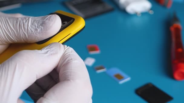 Trabalhador técnico retira bandeja SIM com cartões SIM do smartphone amarelo — Vídeo de Stock