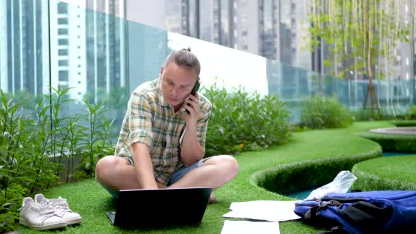 Hombre muy preocupado habla con el teléfono inteligente, buscar información en documentos de papel, utilizar tableta PC — Vídeos de Stock