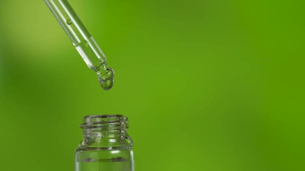 Gota caindo em frasco de vidro com líquido medicinal no fundo gradiente verde — Vídeo de Stock