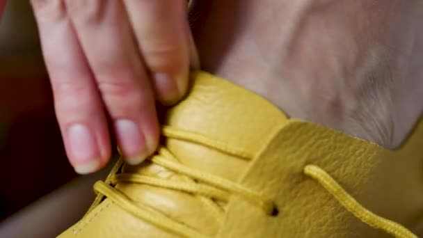 Femme méconnaissable attachant des lacets dans des chaussures jaunes — Video