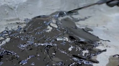 Bituminous su yalıtımı macunu kaba kum-çimento yüzeyine eldivenli elle mala ile uygulanıyor. Yapışkan yapışkan ve su geçirmez. Binaları nemden korumak için kullanılır. Çatlakları mühürle