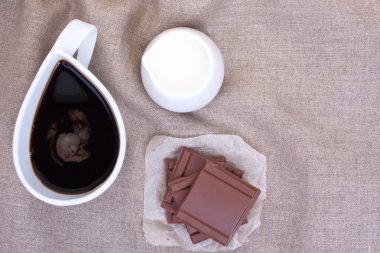 Çikolata parçaları ile keten masa örtüleri üzerinde Fincan kahve, krema