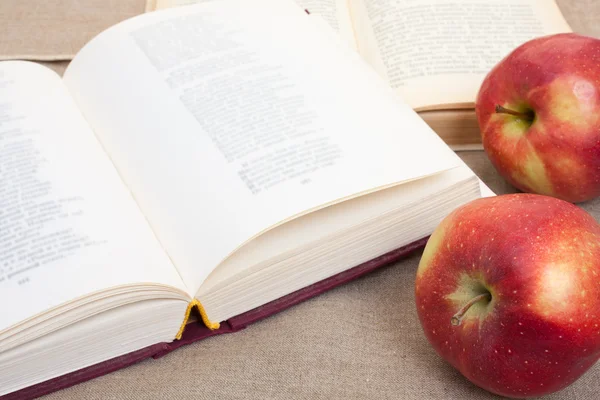 Composition with red apples and opened books on the table, on th